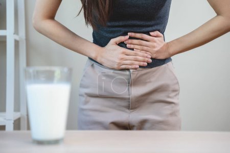 Téléchargez les photos : Lactose intolerance concept. Woman having a stomachache because drink milk. - en image libre de droit