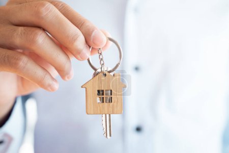Téléchargez les photos : Fermer vue courtier immobilier tenant porte-clés maison dans sa main. - en image libre de droit