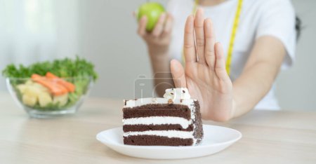 Foto de Comer menos azúcar para la salud, las mujeres evitan comer pastel de chocolate y dulces durante la sesión de dieta de azúcar para perder peso - Imagen libre de derechos