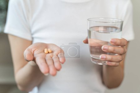 Foto de Close up person pouring multivitamin capsules to her hands - Imagen libre de derechos