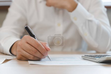 Foto de De cerca la mano del contador profesional revisa el papeleo fiscal y firma la firma sobre la mesa en el lugar de trabajo - Imagen libre de derechos