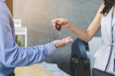 Photo for Concept car rental service. Close up view hands of agent giving car key to client that rent a vehicle  in rental office. - Royalty Free Image
