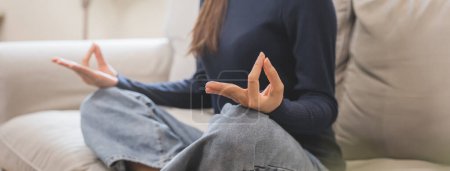 Photo for Well being meditation. Asian women sit in the living room and practice mindfulness by focusing on breath concentrate. - Royalty Free Image
