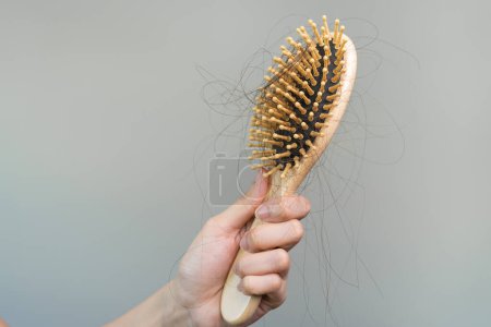 Téléchargez les photos : Concept de problème de chute de cheveux. Choqué femme asiatique regardant beaucoup de cheveux perdus dans sa main et peigne. - en image libre de droit