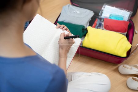 Téléchargez les photos : Person prepare clothes and accessories to luggage before summer vacation trip. - en image libre de droit
