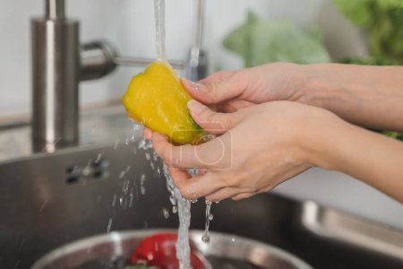 Téléchargez les photos : Gros plan des mains les gens qui lavent les légumes à l'eau du robinet à l'évier dans la cuisine pour nettoyer l'ingrédient préparer une salade fraîche. - en image libre de droit