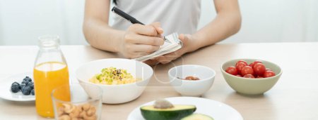 Téléchargez les photos : Menu de planification jeune femme pour manger un régime cétogène pendant le programme de perte de poids. - en image libre de droit