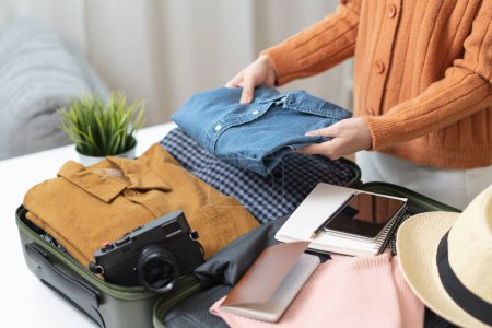 Téléchargez les photos : People check clothes into luggage in suitcase checklist before holidays trip - en image libre de droit