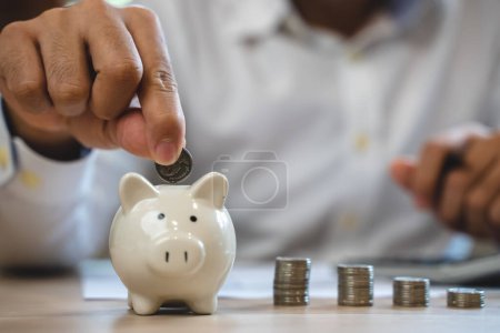 Foto de The person putting coin into piggy bank to save money and invest for growth in future. - Imagen libre de derechos