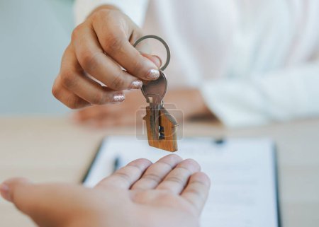 Téléchargez les photos : Close up view hand of property realtor / landlord giving key house to buyer / tenant. - en image libre de droit
