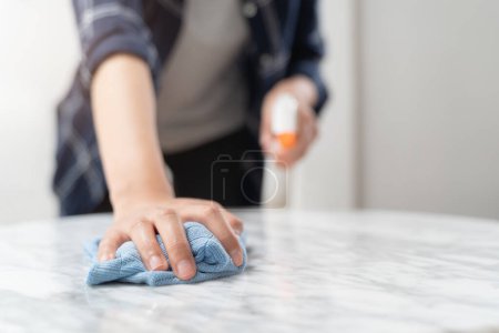 Téléchargez les photos : Asian woman cleaning the table surface with towel and spray detergent - en image libre de droit