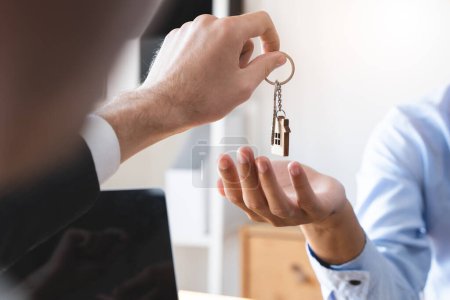 Téléchargez les photos : Vue rapprochée main de l'agent immobilier propriétaire donnant maison clé à l'acheteur locataire. - en image libre de droit