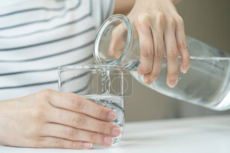 Téléchargez les photos : Concept d'eau douce propre. Femme boire de l'eau minérale le matin pour une bonne santé. - en image libre de droit