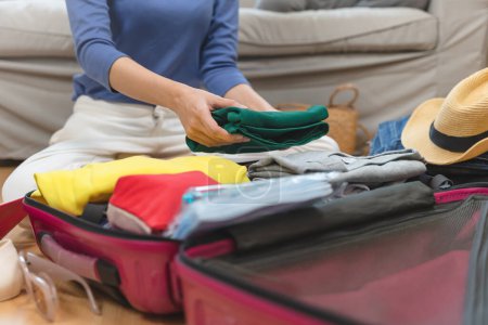 Photo pour Person prepare clothes and accessories to luggage before summer vacation trip. - image libre de droit