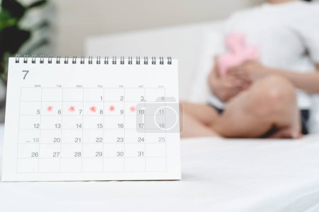 Téléchargez les photos : Menstruation mensuelle symptôme période concept. Fermer calendrier marquage le jour des règles et les femmes ont des douleurs à l'estomac comme arrière-plan. - en image libre de droit