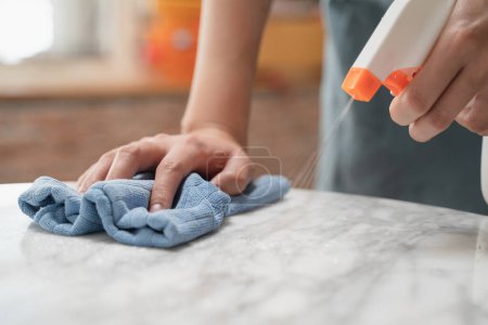 Foto de Asian woman cleaning the table surface with towel and spray detergent - Imagen libre de derechos