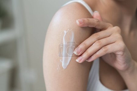 Téléchargez les photos : Body skin care routine concept. Close-up view hands of a young woman applying lotion cream on the shoulder - en image libre de droit