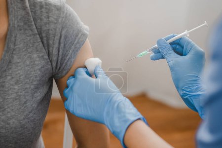 Photo for People getting a vaccination to prevent pandemic concept. Woman in medical face mask  receiving a dose of immunization coronavirus vaccine from a nurse at the medical center hospital - Royalty Free Image
