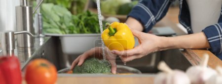 Foto de Primer plano de las manos personas lavando verduras por el agua del grifo en el fregadero de la cocina para limpiar el ingrediente preparar una ensalada fresca. - Imagen libre de derechos