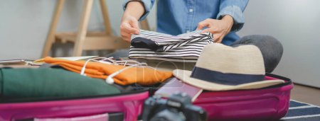 Téléchargez les photos : Les gens qui mettent des vêtements dans leurs bagages préparent une valise avant le voyage de vacances - en image libre de droit