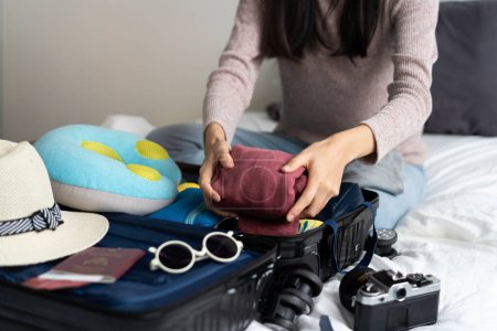 Foto de Preparing suitcase for summer vacation trip. Young woman checking accessories and stuff in luggage on the bed at home before travel. - Imagen libre de derechos