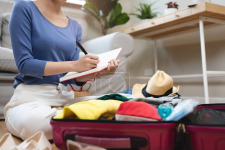 Photo for Person prepare clothes and accessories to luggage before summer vacation trip. - Royalty Free Image