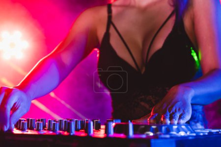 Foto de Sexy disc jockey en el tocadiscos jugando en el club nocturno. DJ mezcla de audio en el club nocturno. - Imagen libre de derechos