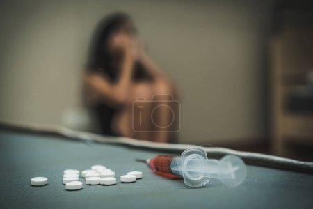 Téléchargez les photos : Fermer les pilules et la seringue sur le lit. Suicide chez la femme déprimée par surdose de drogue. - en image libre de droit