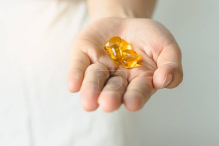 Foto de Close-up view tablet of fish-oil supplement in woman hand. - Imagen libre de derechos