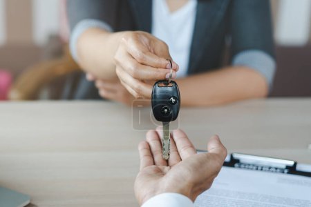 Photo for Car rental service concept. Close up view Hand of agent giving car key to customer after signed rental contract form. - Royalty Free Image