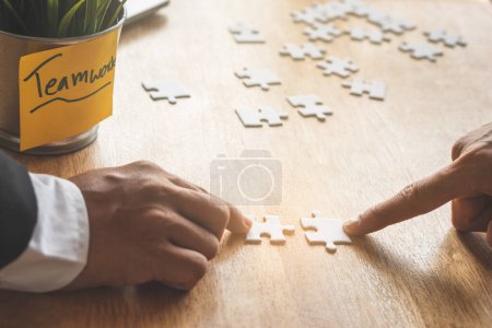 Photo for Teamwork, partners, connection concept. Hands of two businessmen merging jigsaw puzzle on the working table. - Royalty Free Image