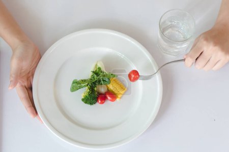 Foto de Come menos y come sano. persona comiendo verduras en la cena durante el control de calorías en la dieta. - Imagen libre de derechos