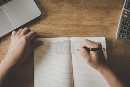 Photo for Close up hand of student writing notes in to notebook. - Royalty Free Image