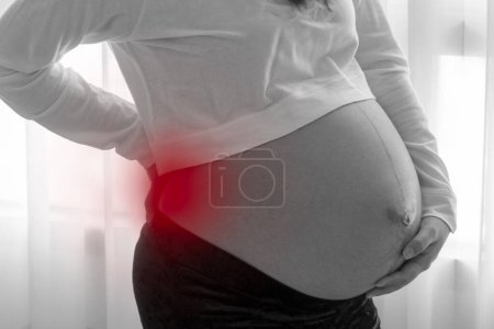 Téléchargez les photos : Pregnant women having back ache from weight of baby before birth. black and white. - en image libre de droit