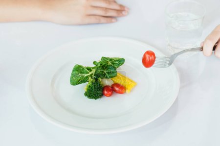 Photo for Eat less and eat healthy. person eating vegetable in dinner during control calories on dieting. - Royalty Free Image