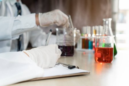 Photo for Group of college student doing chemical laboratory test during chemistry classroom. Student taking note of laboratory result. - Royalty Free Image