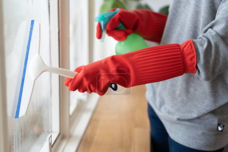 Téléchargez les photos : Housekeeper cleaning home concept. Woman spraying cleanser to window. - en image libre de droit