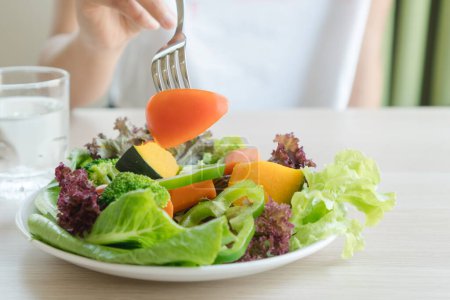 Foto de Menú de comida para personas dietéticas. mujeres comiendo tomate en verduras de variedad en plato de ensalada durante la dieta. - Imagen libre de derechos