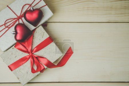 Photo for Valentine day background. Top view of gift boxes and two red heart on the wooden table background vintage style. have a copy space for text. - Royalty Free Image