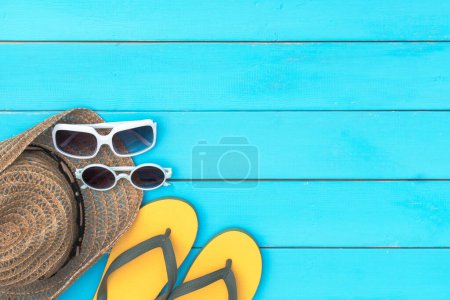 Foto de Sandalia y gafas de sol y conchas marinas sobre fondo rústico de madera azul. tener un espacio de copia para el texto. - Imagen libre de derechos