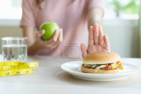 Photo for Woman on dieting for good health concept. Woman doing cross arms sign to refuse junk food or fast food (hamburger and potato fried) that have many fat. - Royalty Free Image