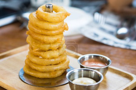 Photo for Delicious homemade appetizer. fried onion rings stack look like the tower serve with dip sauce on wooden tray. - Royalty Free Image
