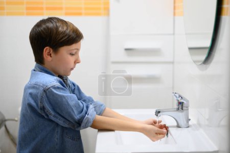 Photo for Child turns on water faucet in a restroom - Royalty Free Image