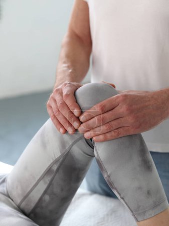 Thérapeute traitant le genou d'une athlète patiente. Ostéopathie et physiothérapie traitement du genou.