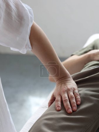 Thérapeute somatique travaillant avec genou blessé du patient masculin. Concept de physiothérapie et de réadaptation