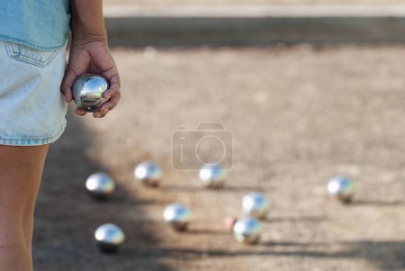 Téléchargez les photos : Senior playing petanque un and relaxing game, balls on the ground. Senior woman prepared to throw the boules ball in a park in outdoor play - en image libre de droit