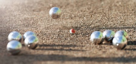 Foto de Petanque ball boules bowls on a dust floor, photo in impact. Game of petanque on the ground. Balls and a small wood jack - Imagen libre de derechos