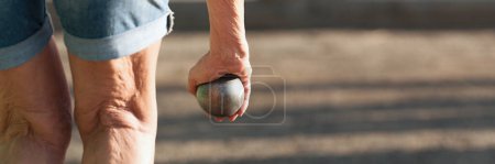 Photo for Senior playing petanque un and relaxing game. Senior woman prepared to throw the boules ball in a park in outdoor play - Royalty Free Image
