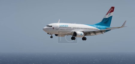 Téléchargez les photos : Tenerife, Espagne 2 août 2023. Boeing 737-700 de Luxair Airlines vole dans le ciel bleu au-dessus de l'océan - en image libre de droit