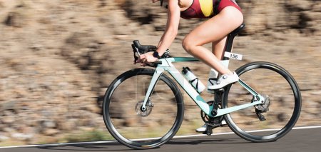 Photo for Motion blur of a bike race with the bicycle and rider at high speed. Professional female cyclist in racing in triathlon clothing outfit during a ride on bike outdoors. Panning technique used - Royalty Free Image